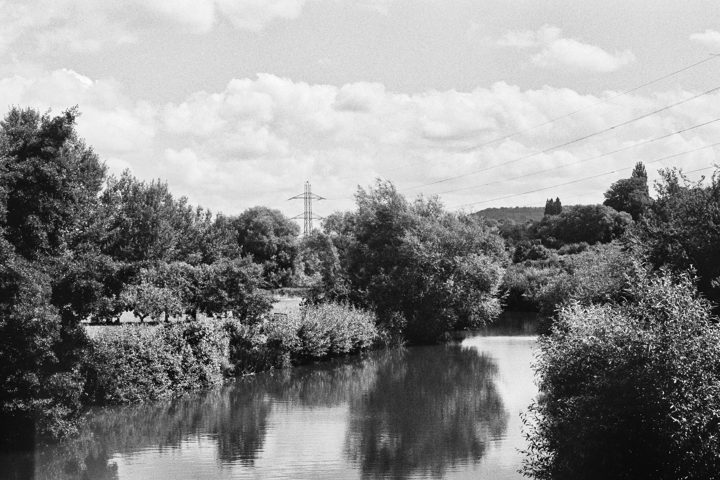 A black and white photograph of power lines going over a river