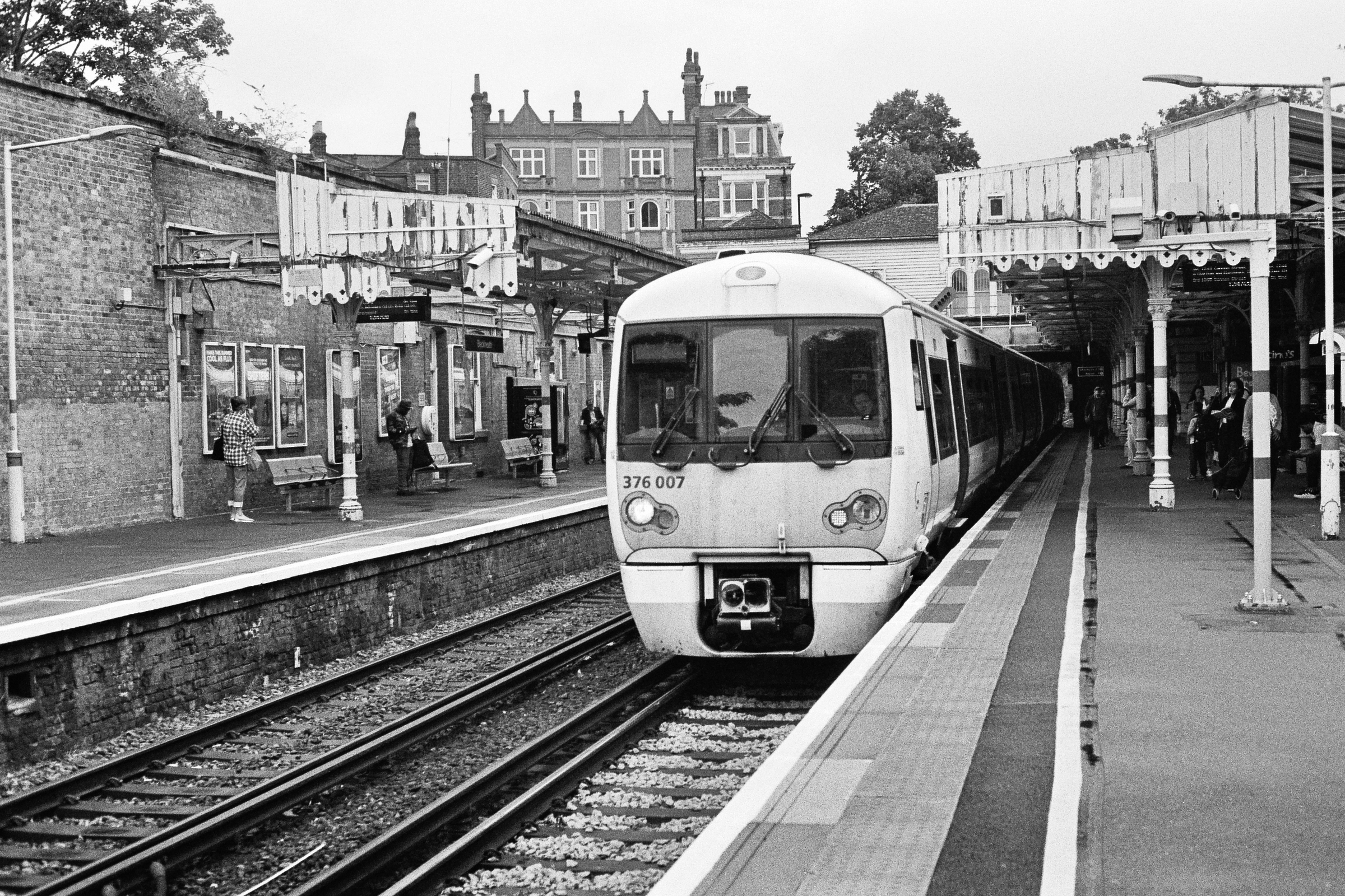 A black and white photograph of a train pulling into a station