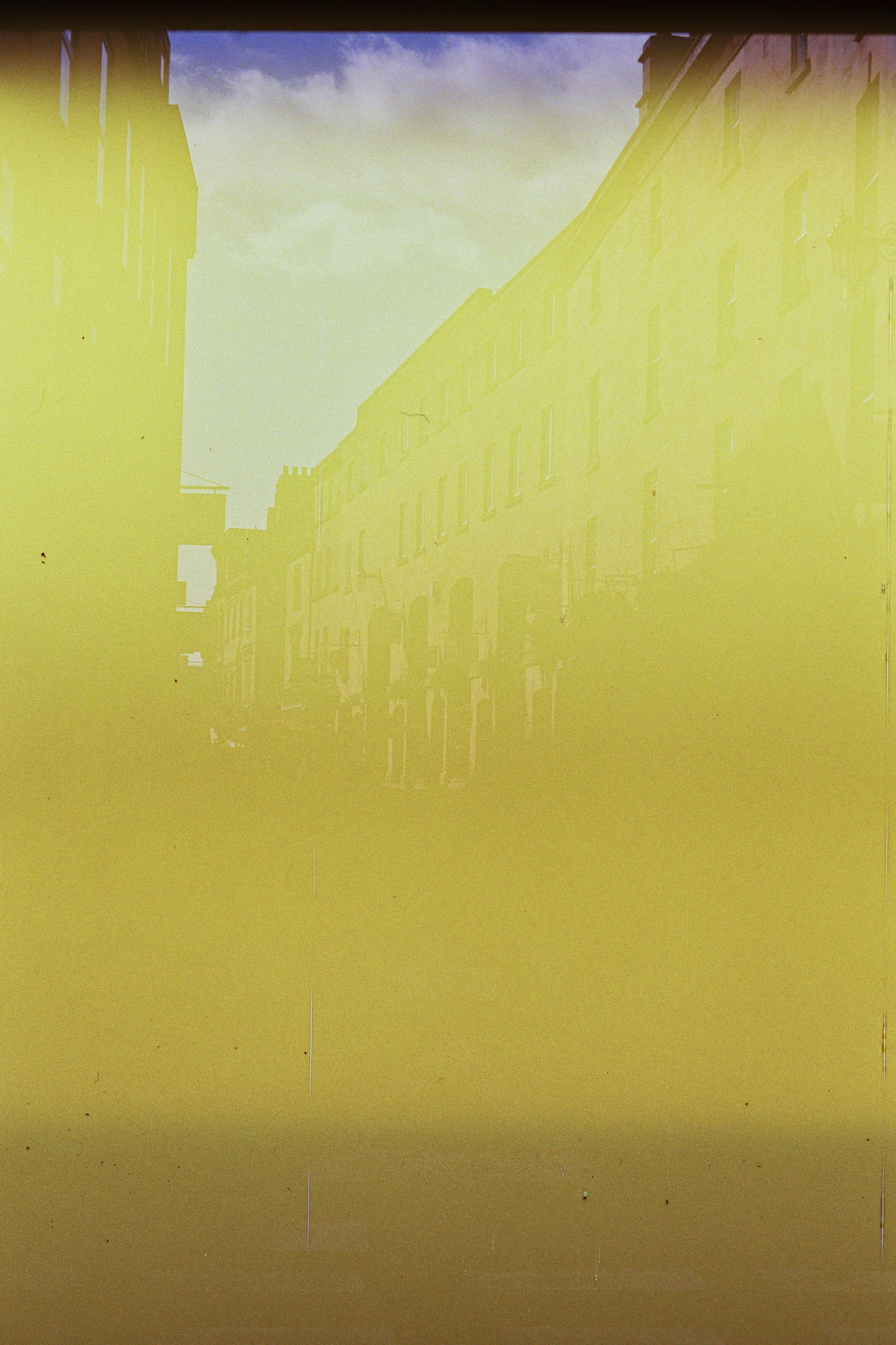 A photograph of a street, with a yellow tint over the entire photo