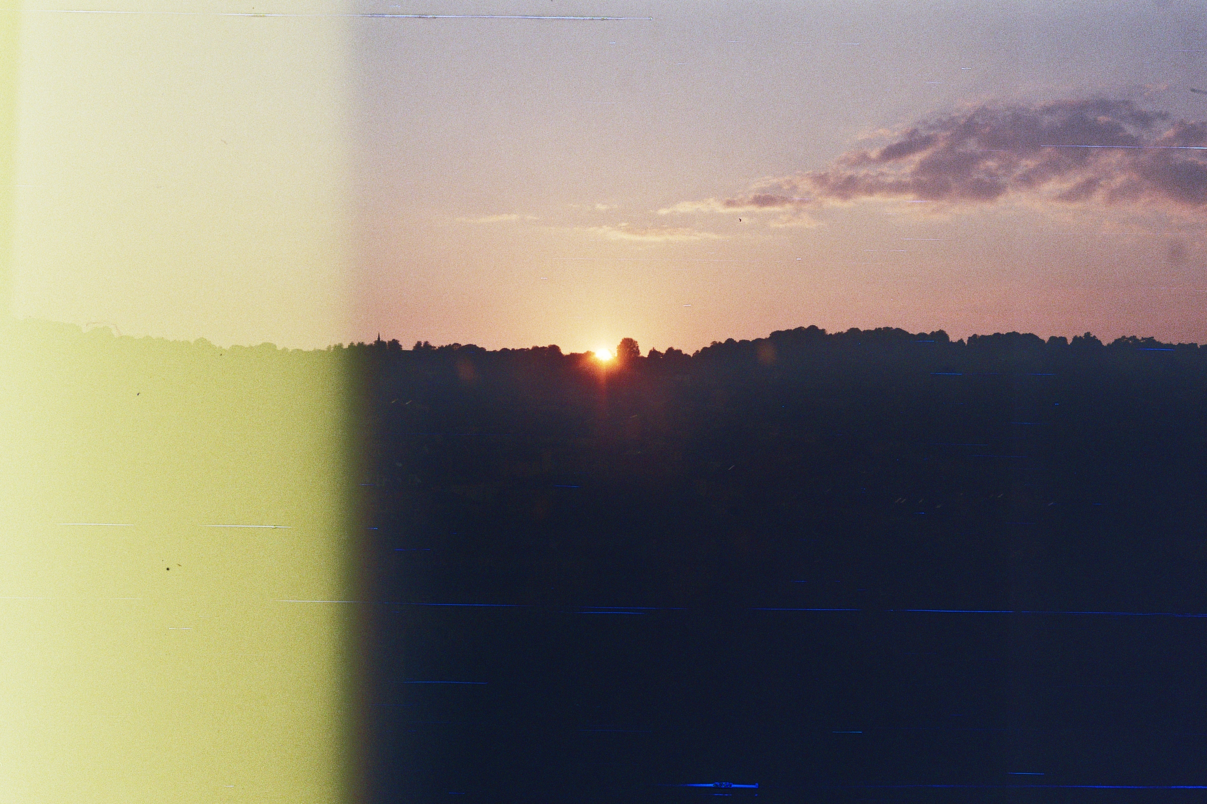 A photograph of a sunset,with a yellow stripe on the left of the photo